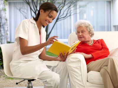 Nurse seeing a book with elderly woman on sofa