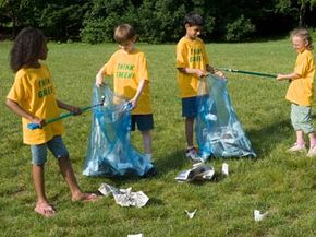 Children cleaning up trash in park.