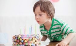 A young child blows out candles on a birthday cake.