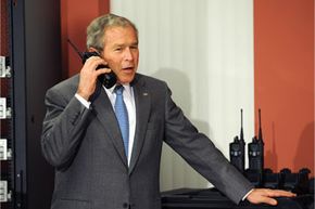 U.S. President George W. Bush speaks on a walkie-talkie during a tour of World Wide Technology, Inc. in 2008.