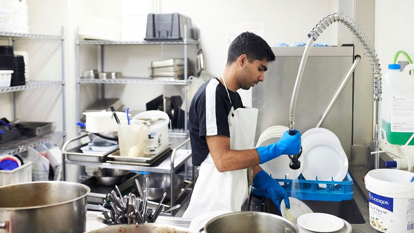 man washing dishes in commercial kitchen