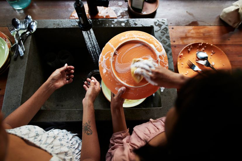 Directly above shot of mother and daughter washing dishes near sink in kitchen during vacation