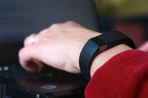 一名员工穿着Fitbit在笔记本电脑上打字。一项研究显示，不到一半的美国人对工作场所的可穿戴设备有隐私担忧。＂border=