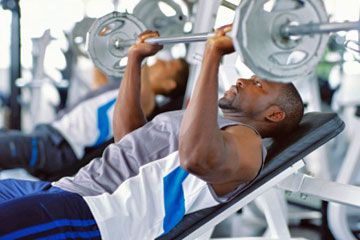Two mid adult men exercising in a gym with weights