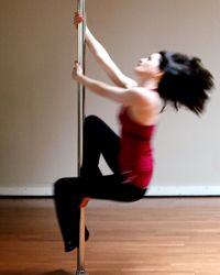 Actress Sheila Kelly, developer of a pole dancing workout, spins on a pole.