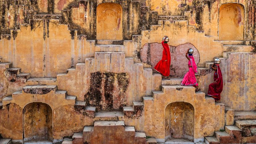 印度妇女从stepwell提水”border=