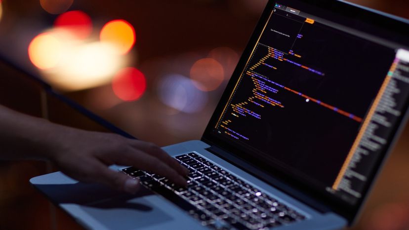 Person's hand typing code into an algorithm on a computer.