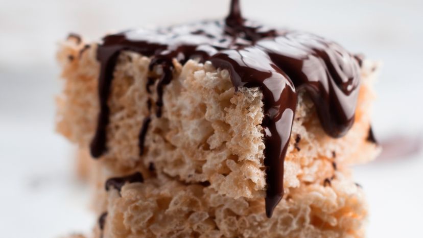 Chocolate dripping being poured on a stack of rice krispies. 