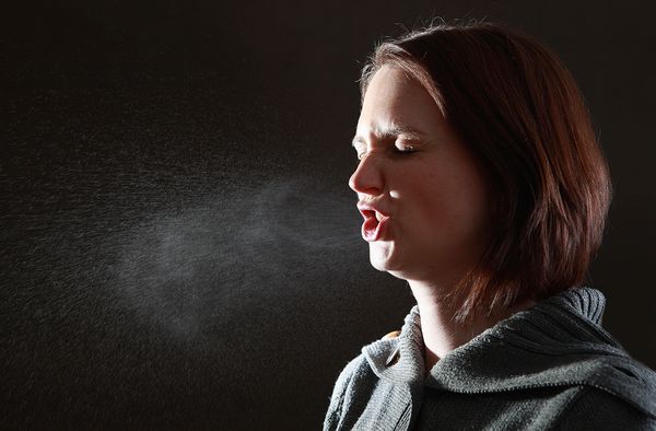 Woman sneezing in studio setting