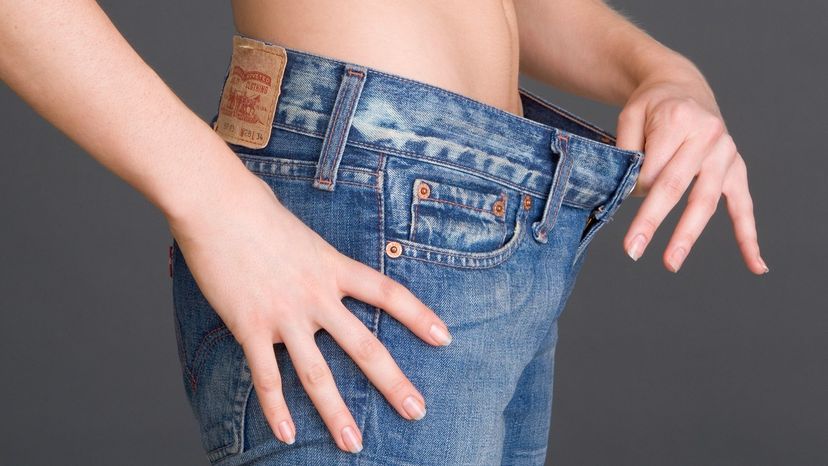 Woman holding loose waistband of jeans