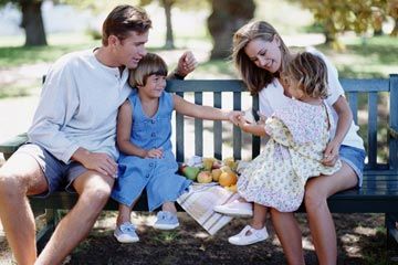 Two parents sit on bench with two daughters