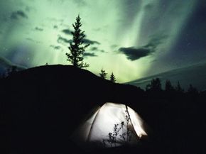 The Northern Lights shine beyond a tent in the MacKenzie Mountains in Canada