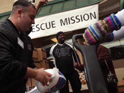 A volunteer for a rescue mission gives a turkey and a box of food to a needy family at the annual Thanksgiving Banquet in a Box distribution in Denver, Colorado, November 2008.