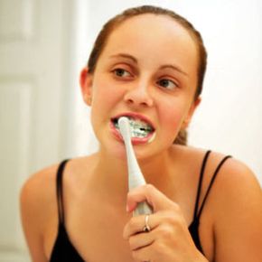 girl with braces brushing teeth