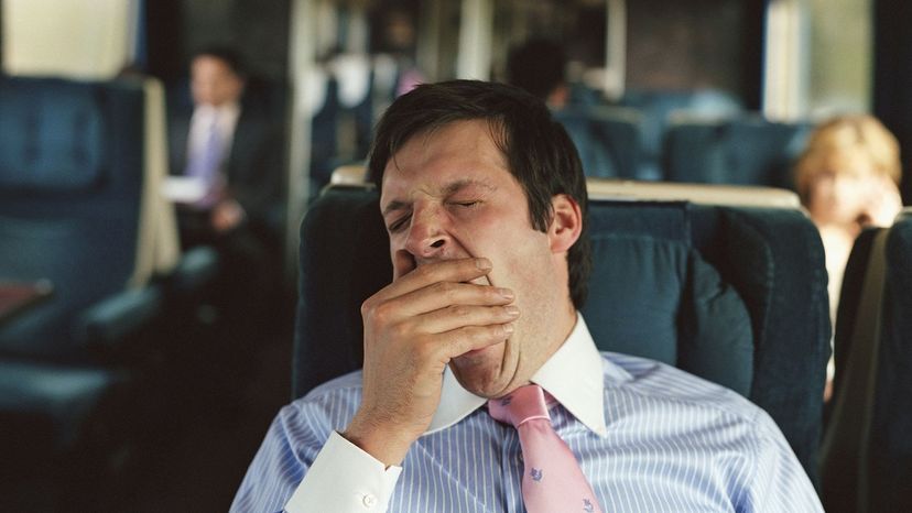 businessman yawning on train