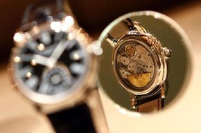 在瑞士巴塞尔举行的2009年巴塞尔钟表珠宝展上，一块百达翡丽腕表的背面倒映在镜子里。＂border=