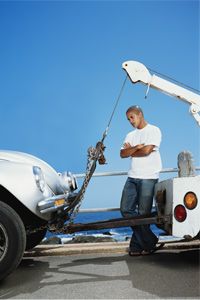 man watches car getting towed