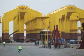 在北海风电场中，这些巨大的三叉钢腿是固定每个涡轮机所必需的，这一要求使得一些海上建设的成本过高。＂border=
