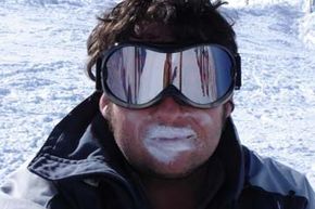 Man with excessive sunblock and large goggles on the slopes.