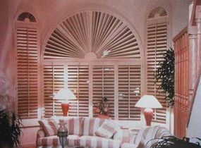 © Shutters unify this arrangement of a large central window flanked by tall, thin sidewindows. A custom sunburst design repeats at the tops of the three windows.