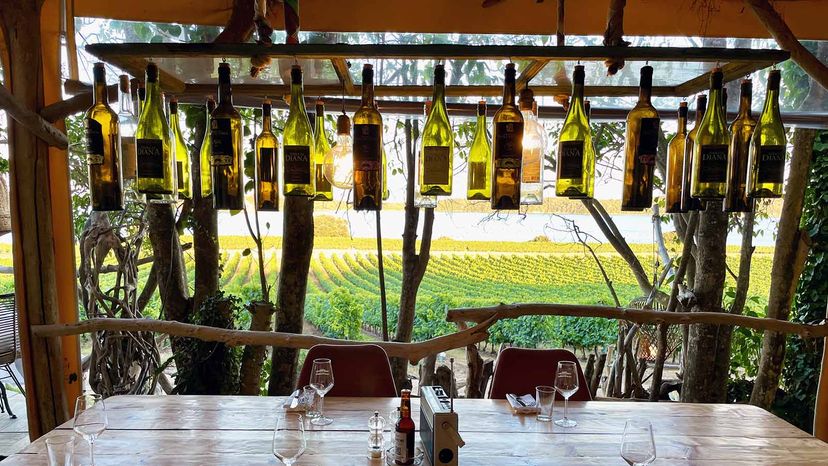 Aleria, Corsica, 5.08.2021. Dining area at Domaine Terra Vecchia, a Corsican vineyard between sea and mountains at Etang de Diana. Retro light lamp decor made of empty wine bottles.