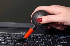 Woman using a special brush to clean computer keys.