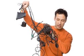 Young man trying to untangle a dozen electronic charging cables.&nbsp;