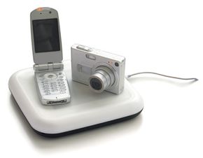 A cell phone and digital camera charging on a wireless charger.