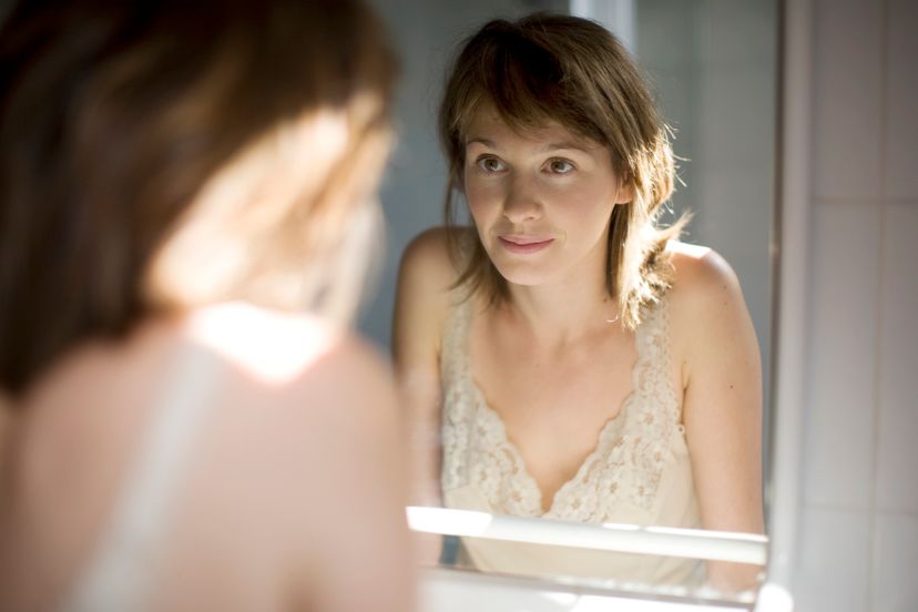 portrait of a woman wathching herself in a mirror and smiling