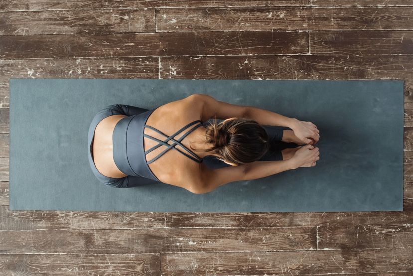 yogi woman, top view, practicing yoga on a mat on the floor, doing stretching in a relaxed pose.