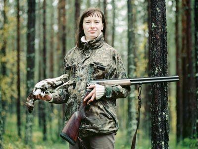 Hunter with rifle in outdoor forest.