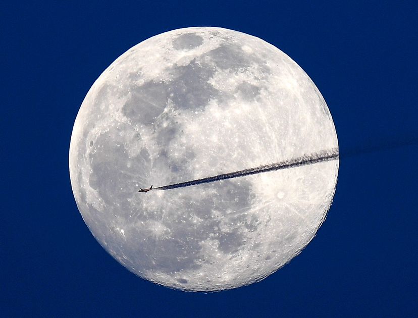 A jet flies northbound as the nearly full worm moon rises March 8, 2020, in Washington, D.C.  Jonathan Newton/The Washington Post via Getty Images