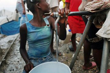 Haitian girl filling jug of water