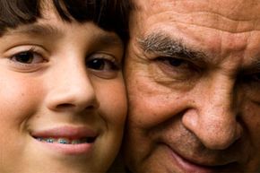 Close up picture of the faces of a hispanic senior man and his eleven years old grandchild