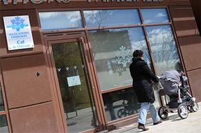 A woman walks with her child in a stroller by a Family Allowance Fund (FAF) office in France. The FAF gives cash assistance to families, particularly those with three or more children; it's one way France encourages childbearing.