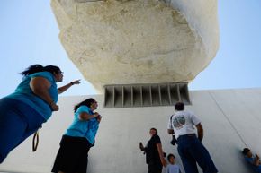 Visitors stand beneath the "Levitated Mass."”border=