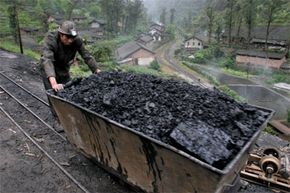 A miner pushes a cart loaded with coal at Bagou village, in China's southwest Sichuan province, on April 13, 2006.