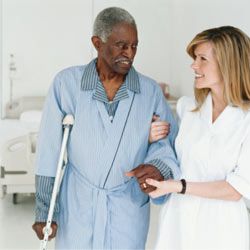 nurse helping senior man walk with crutches