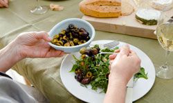 woman adding olives to salad