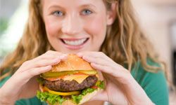 teenage girl eating cheeseburger