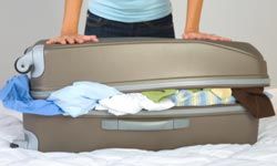 woman trying to close an overpacked suitcase