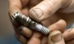 Dirty hands holding spark plug