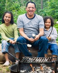 african american man and children roasting marshmallows over a campfire