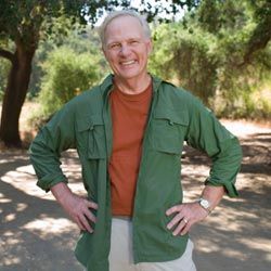 senior man standing by trees at a campsite