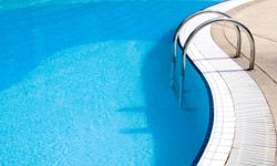 Blue water glistens in swimming pool staircase.