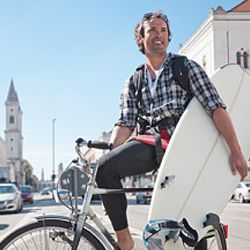 Man riding bike and holding a surfboard