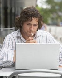 Young man smoking and using laptop