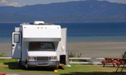 RV parked by lake and mountains