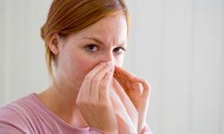 Caucasian woman blowing her nose