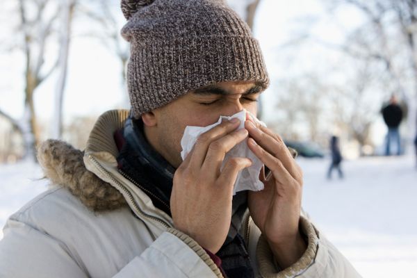 A man blows his nose outdoors.